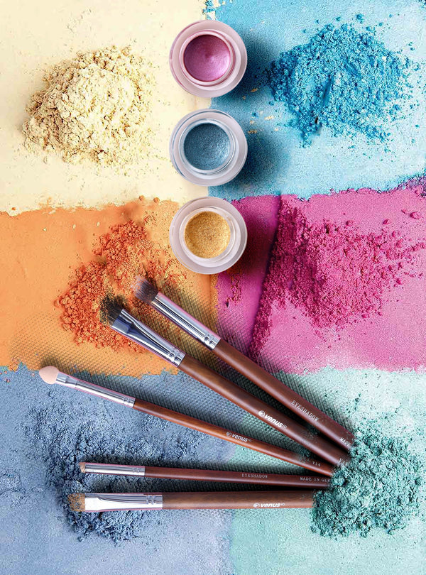 Poudres de maquillage nacrées colorées et pinceaux posés à plat