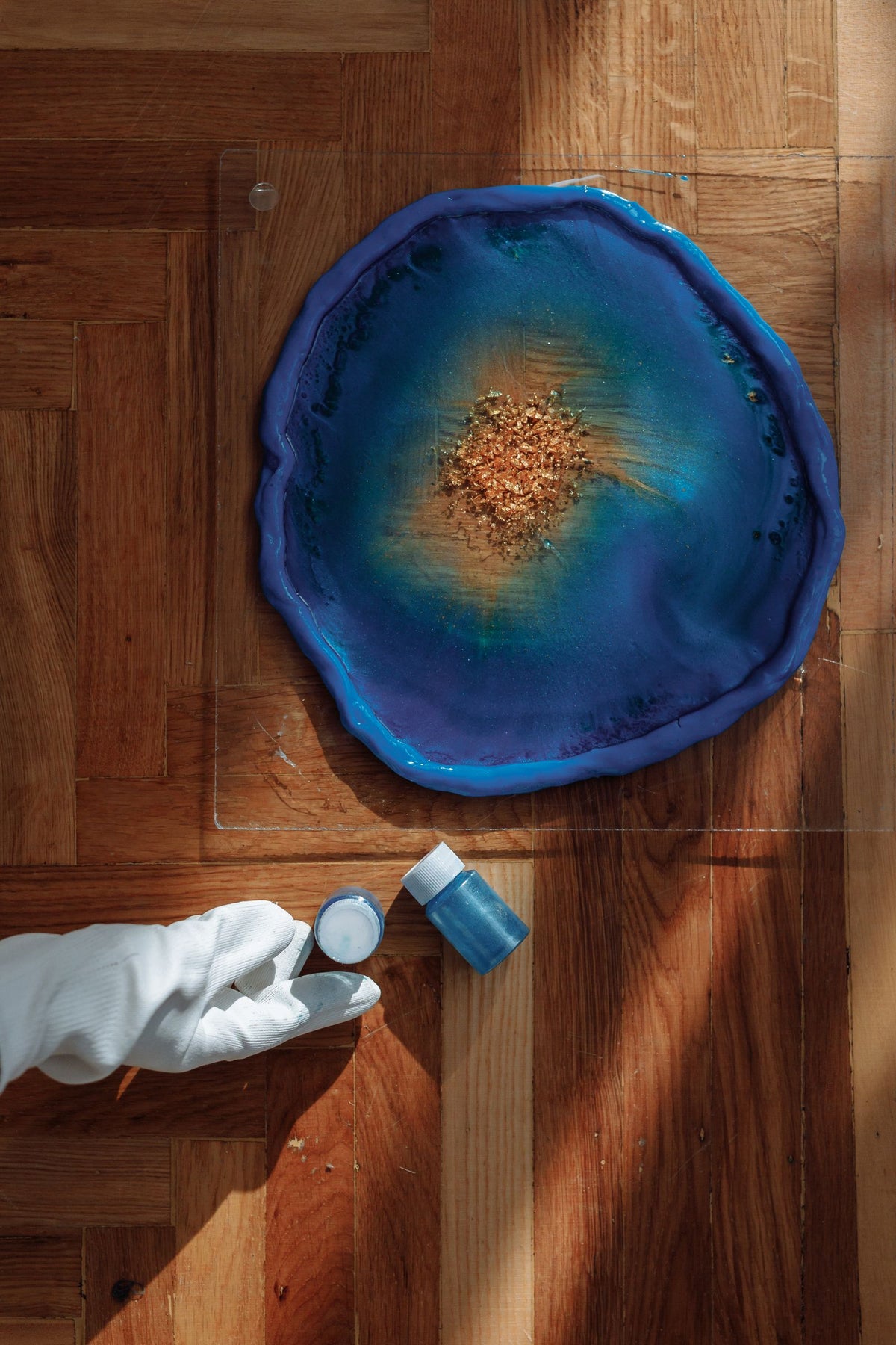 Création en résine colorée en cours de durcissement dans un moule, avec un pot de pigment